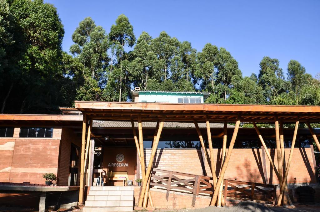 a building with a wooden roof with trees in the background at Pousada Flora Bamboo Eventos in Chapecó