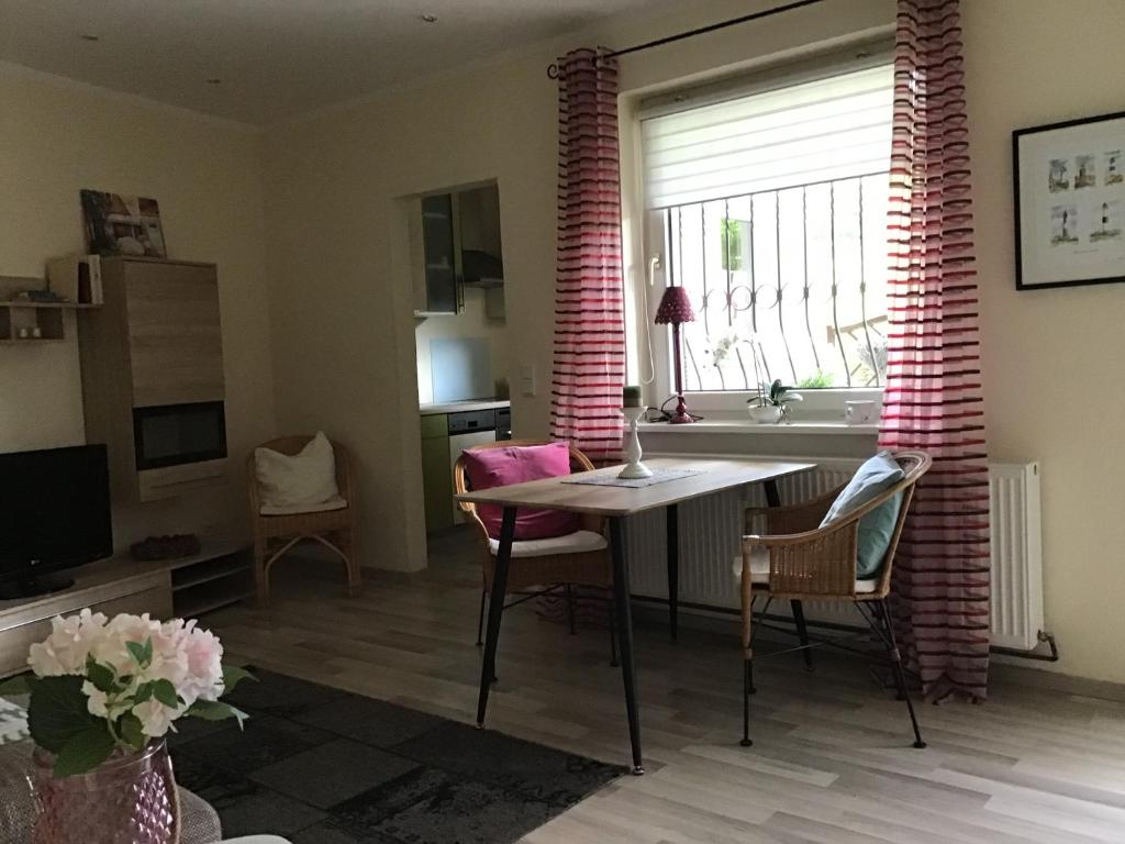 ein Wohnzimmer mit einem Tisch, Stühlen und einem Fenster in der Unterkunft Ferienwohnung Holland 5a in Lügde