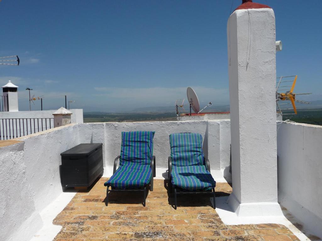 two blue chairs and a tv on a balcony at Casa Sol in Vejer de la Frontera