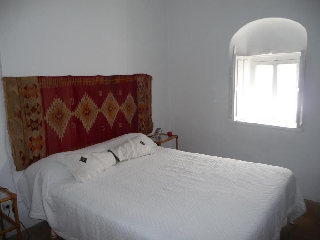 a bedroom with a white bed with a window at Casa Sol in Vejer de la Frontera