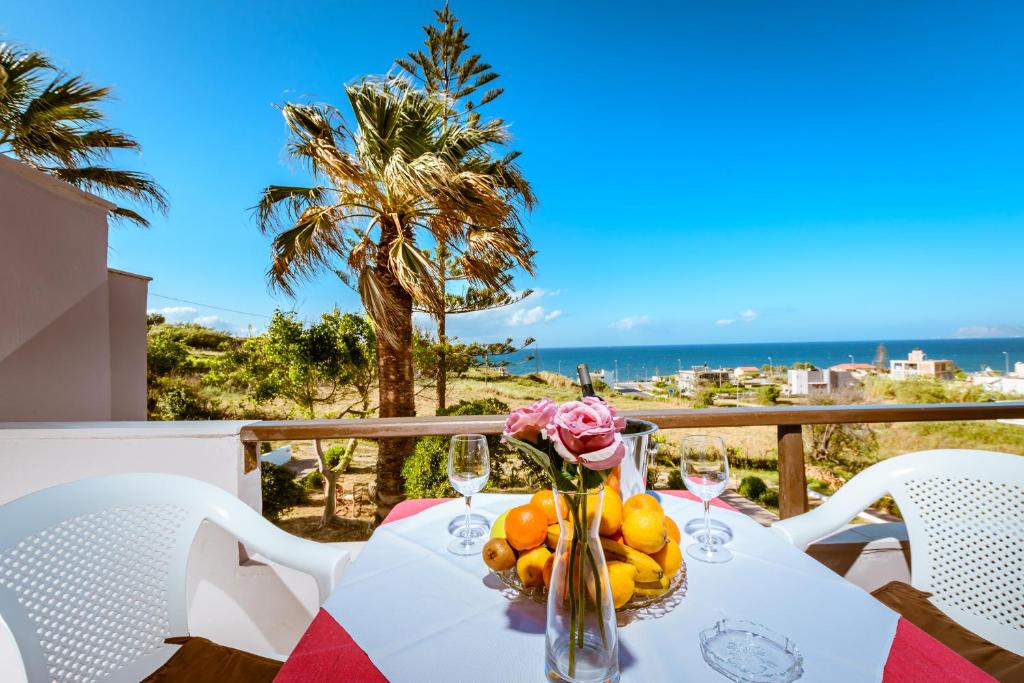 a table with a vase of fruit and flowers on a balcony at Gregory Village Sea View in Stalos