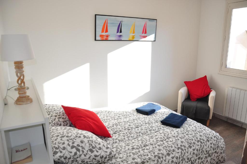 a bedroom with a bed with red pillows and a sail on the wall at Appartement cosy refait à neuf au coeur de Saint Nazaire à 300m du front de mer in Saint-Nazaire