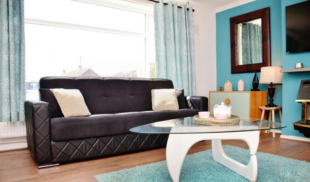 un soggiorno con divano nero e tavolo di 7SM Dreams Unlimited Serviced Accommodation- Stanwell-Staines-Heathrow a Stanwell