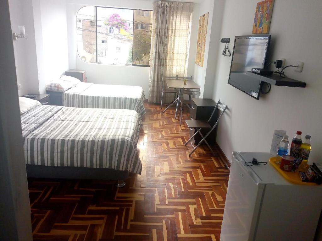 1 dormitorio con 2 camas y suelo de madera en Peruvian Family Hostal Miraflores, en Lima