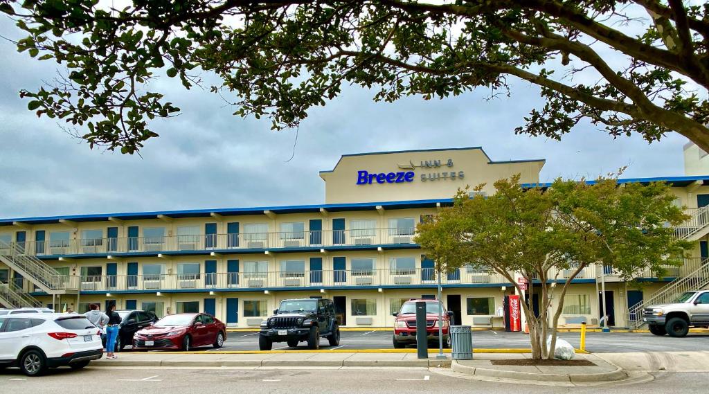 een groot hotel met auto's geparkeerd op een parkeerplaats bij Breeze Inn & Suites, Virginia Beach in Virginia Beach