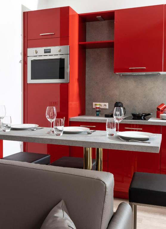 une cuisine avec des placards rouges et une table avec des verres à vin dans l'établissement Appartements French Riviera Confidential Centre Ville Juan les Pins proche des plages, à Juan-les-Pins