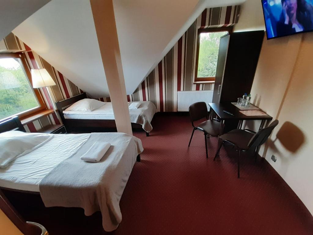 ズギェシにあるRoute One - Restauracja & Pokoje Hoteloweのベッド2台、テーブルと椅子が備わるホテルルームです。