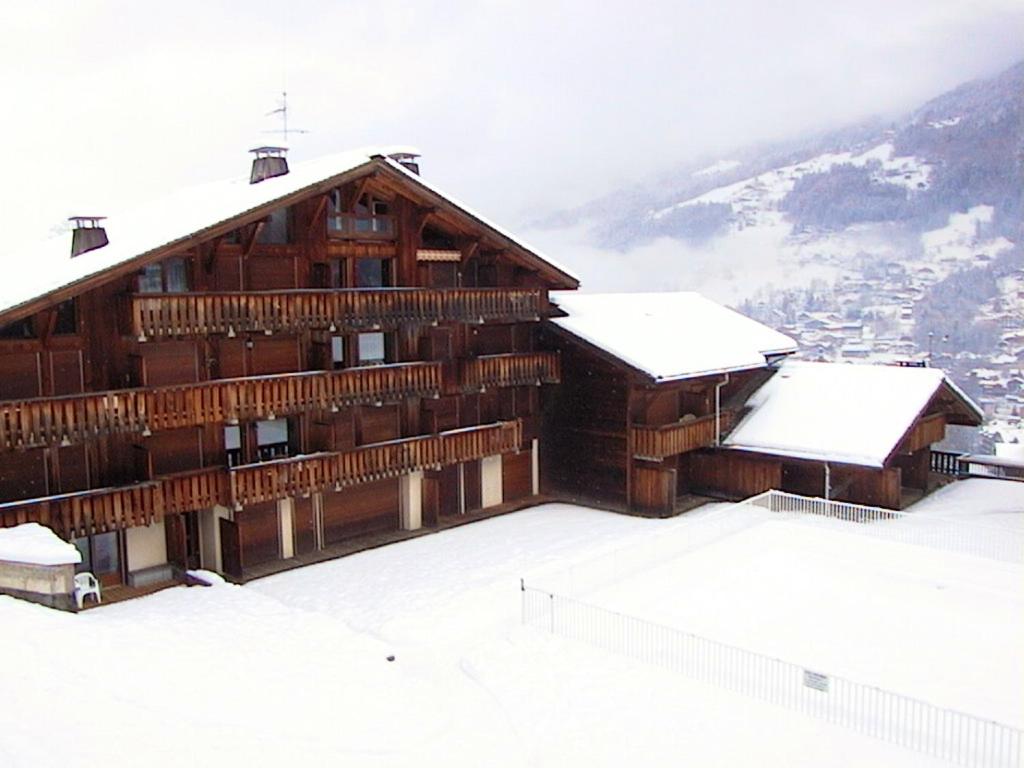 un grand bâtiment en bois avec de la neige sur le toit dans l'établissement Appartement agréable à Saint-Gervais-les-Bains de 30 m² avec piscine, à Saint-Gervais-les-Bains