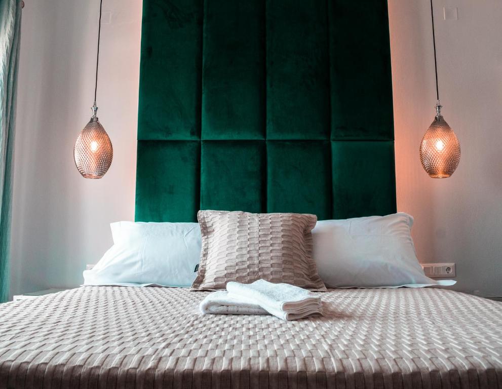 una camera con un letto con testiera verde e un letto con due lampade di DIIO Suites a Ermoupoli