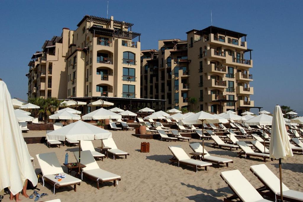 un montón de sillas y sombrillas en una playa en Apartments Oasis VIP Club en Sunny Beach