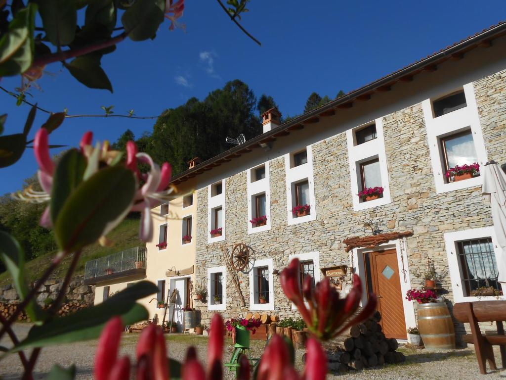 ein Gebäude mit roten Blumen davor in der Unterkunft Agriturismo La Casa Nei Boschi in Colderù