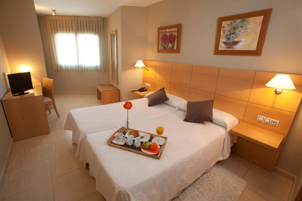 a hotel room with a bed with a tray of fruit on it at La City Estación in Alicante