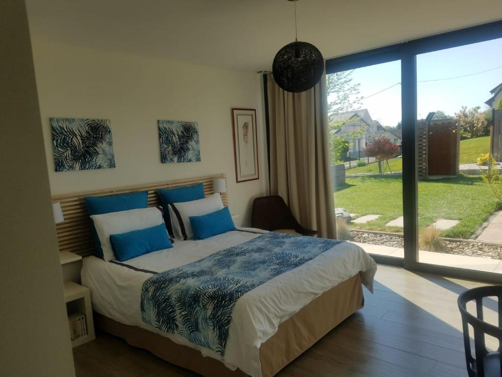 um quarto com uma cama e uma grande janela em Le Jardin des Pies em Manspach