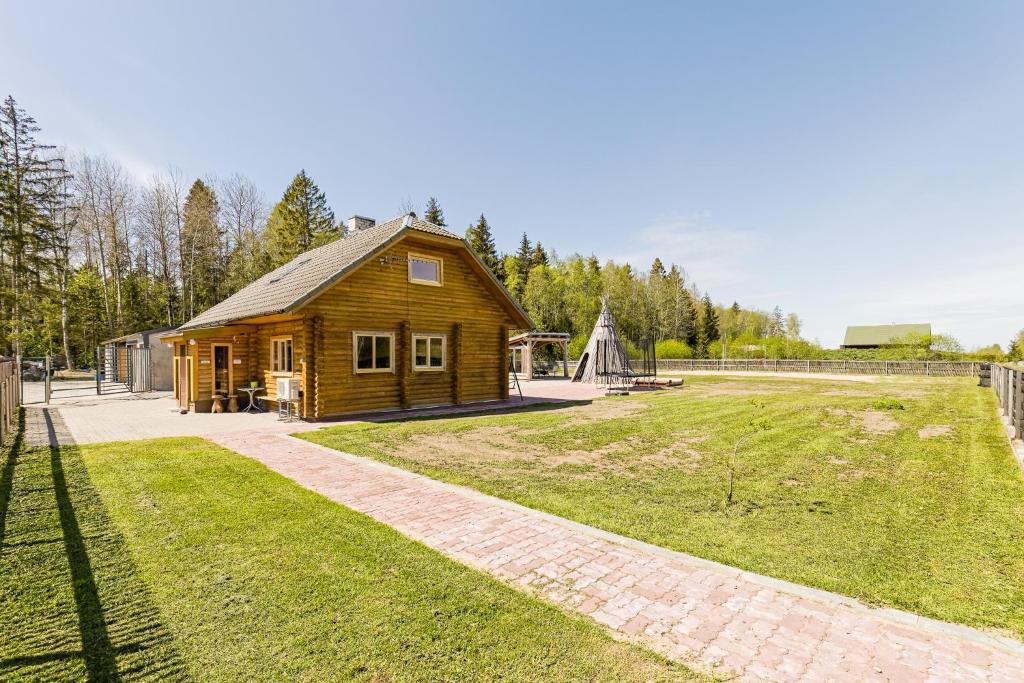 a wooden cabin with a grassy yard next to a building at Kajamaa Holiday Home in Saku