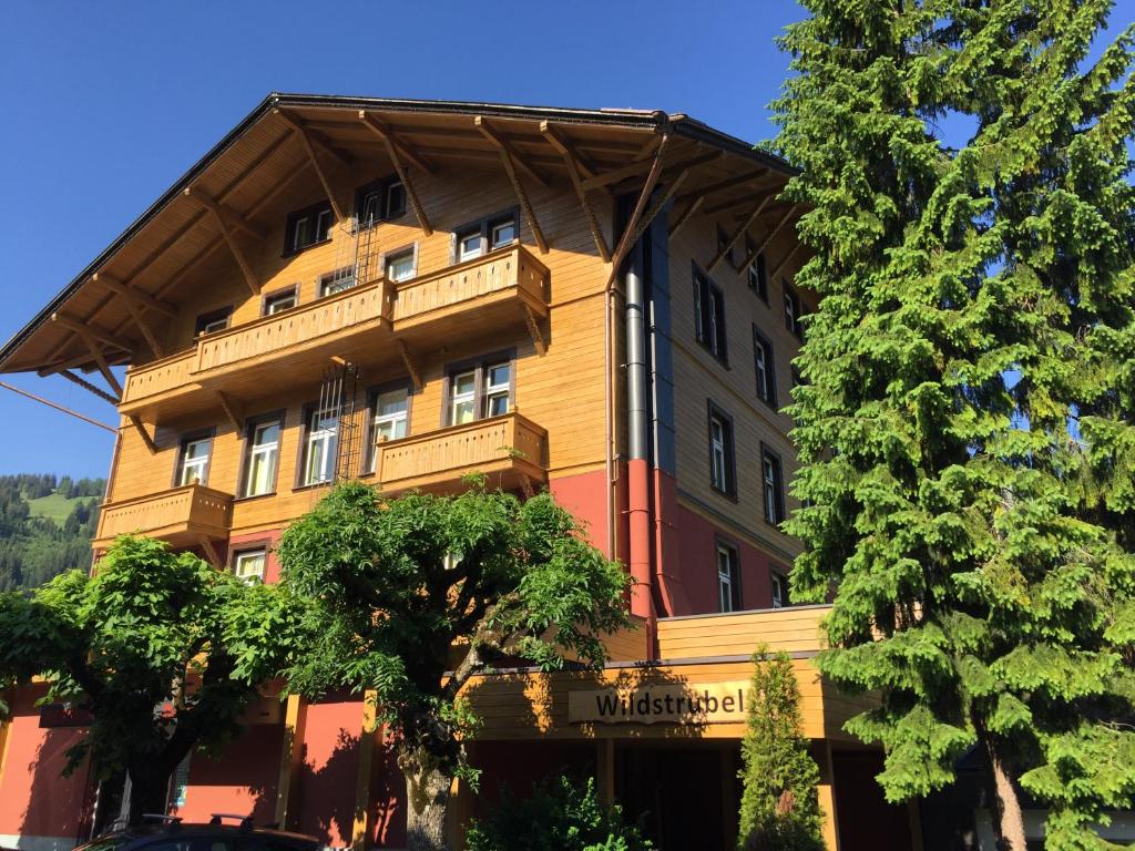 a large wooden building with a gambrel roof at Sporthotel Wildstrubel in Lenk