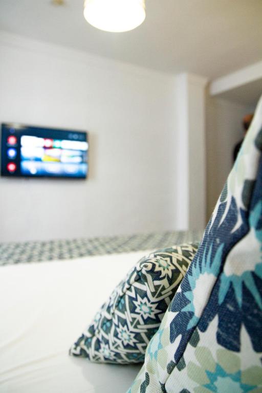 a bedroom with a couch with pillows and a tv at Hotel Avenida Playa in Zahara de los Atunes