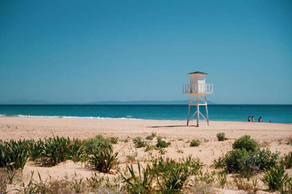 a lifeguard tower on a beach with people in the water at Hotel Avenida Playa in Zahara de los Atunes