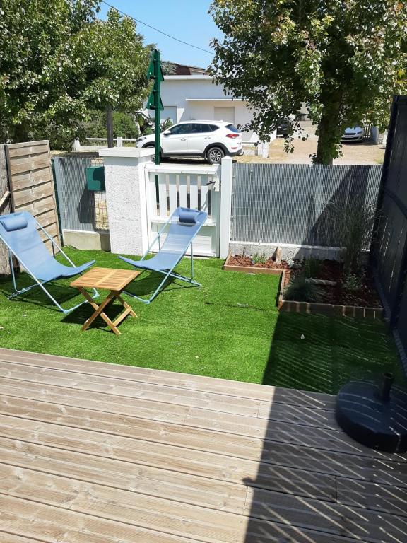 two chairs and a table in a yard at joli duplex proche commerces et mer in Stella-Plage