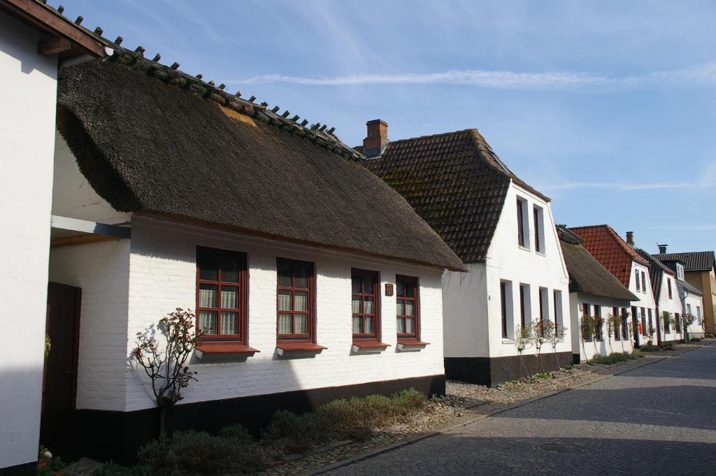 Une rangée de maisons blanches avec fenêtres rouges sur une rue dans l'établissement Altes Fischerhaus, à Maasholm