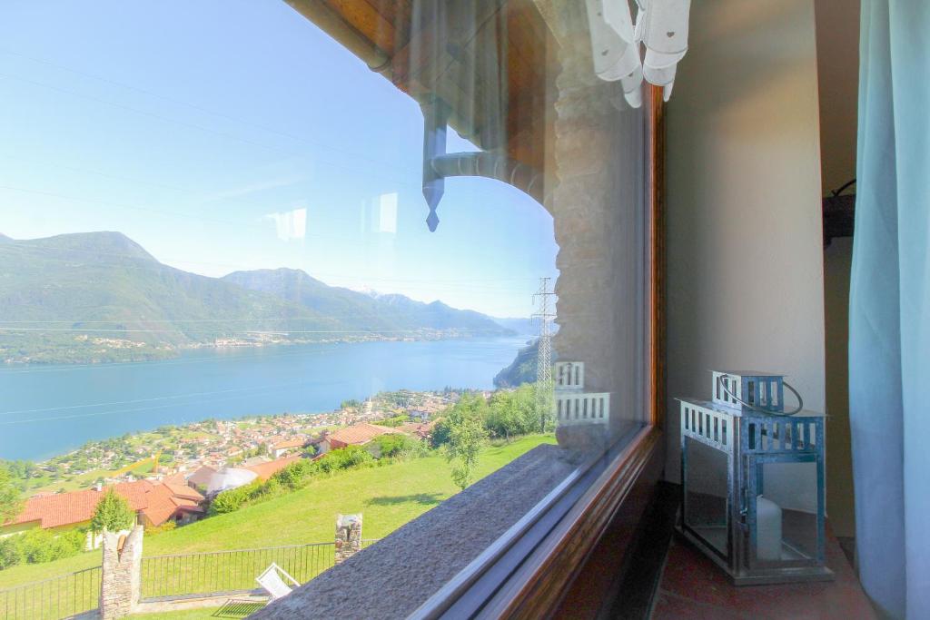 une fenêtre avec vue sur l'eau et les montagnes dans l'établissement Residenza Castellum, à Stazzona
