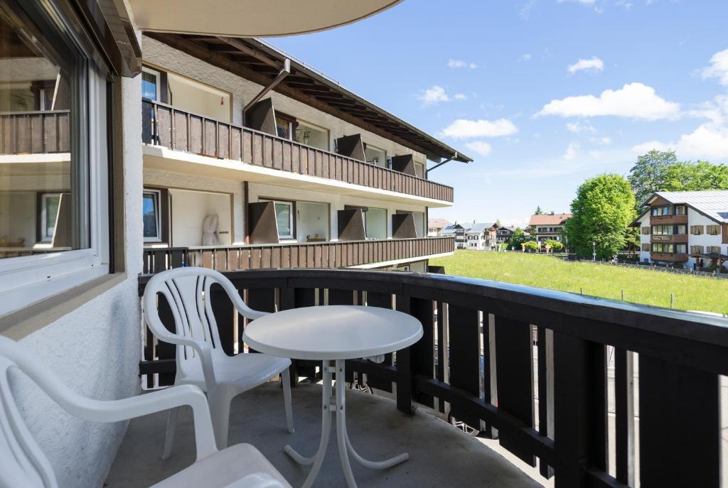 d'un balcon avec des chaises blanches, une table et une fenêtre. dans l'établissement Ferienwohnung Volkmer, à Oberstdorf