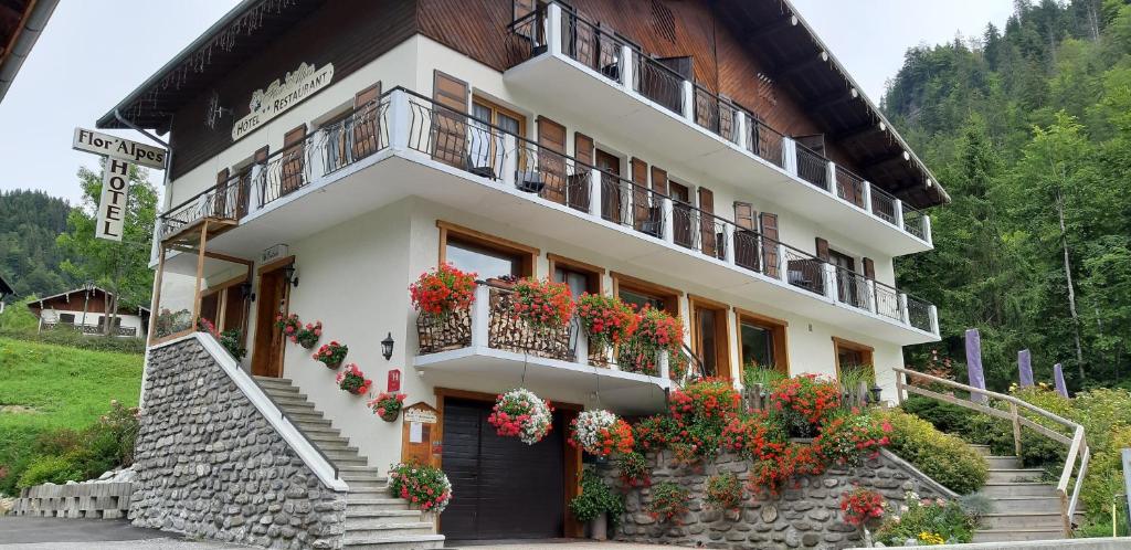 un bâtiment avec des boîtes de fleurs et des balcons. dans l'établissement Hôtel Flor'Alpes, à La Giettaz
