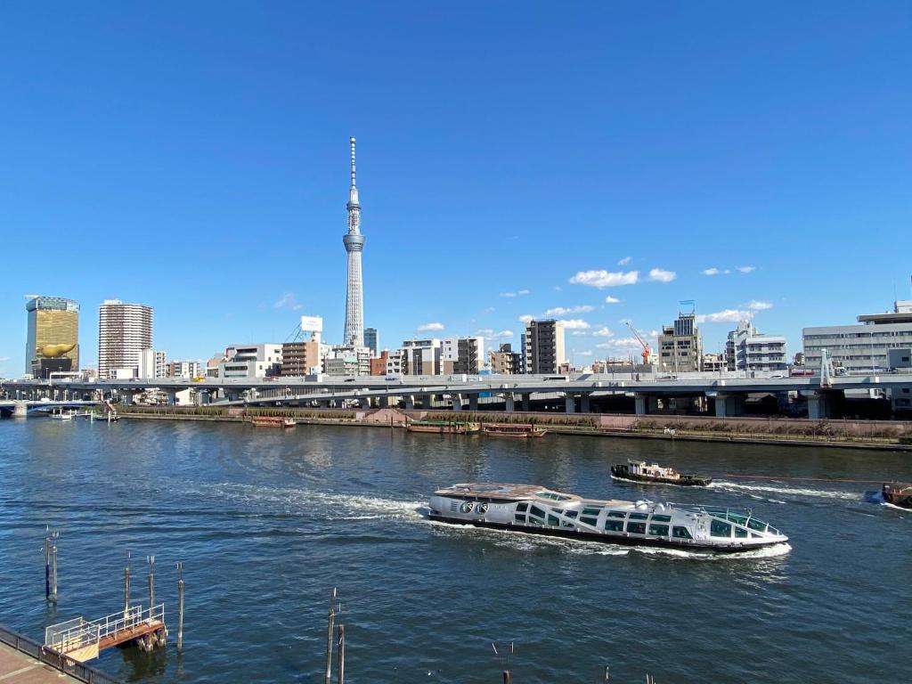 ein Boot auf einem Fluss mit einer Stadt im Hintergrund in der Unterkunft Feel Asakusa Stay in Tokio