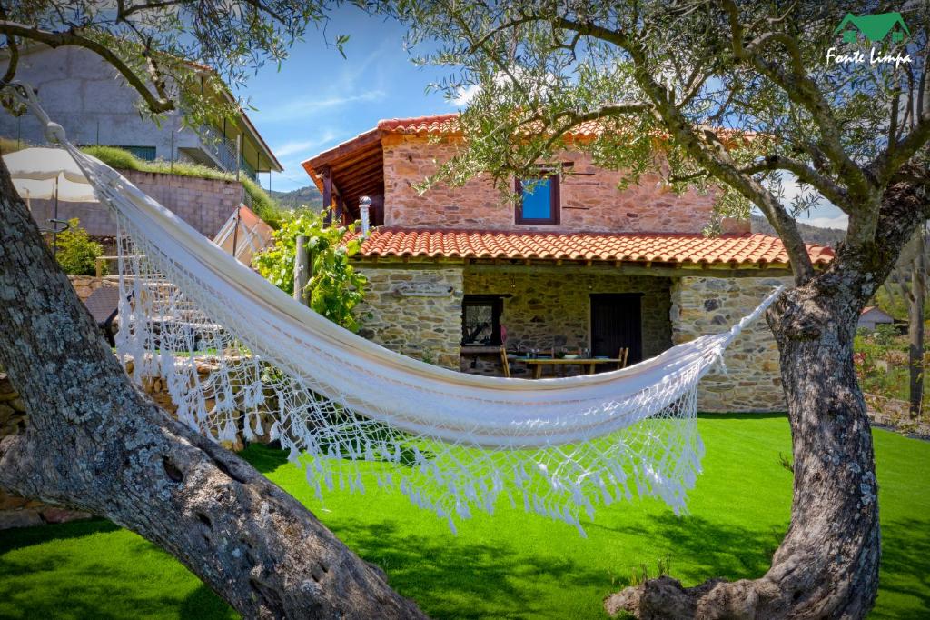 a hammock hanging from two trees in front of a house at Casa da Fonte Limpa in Mirandela