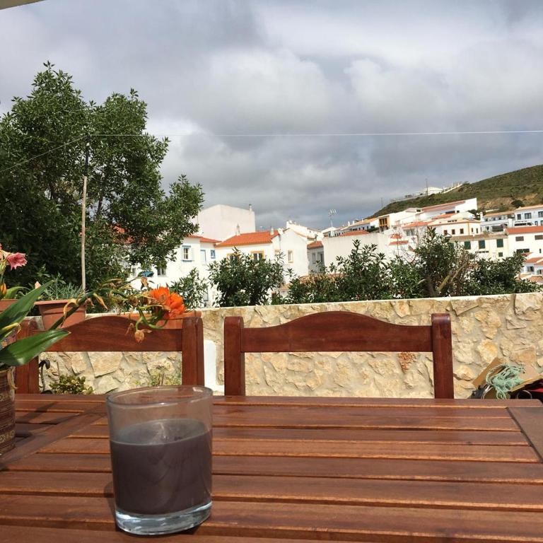 a drink on a wooden table with a view of a city at Carrapateira Lodge in Carrapateira