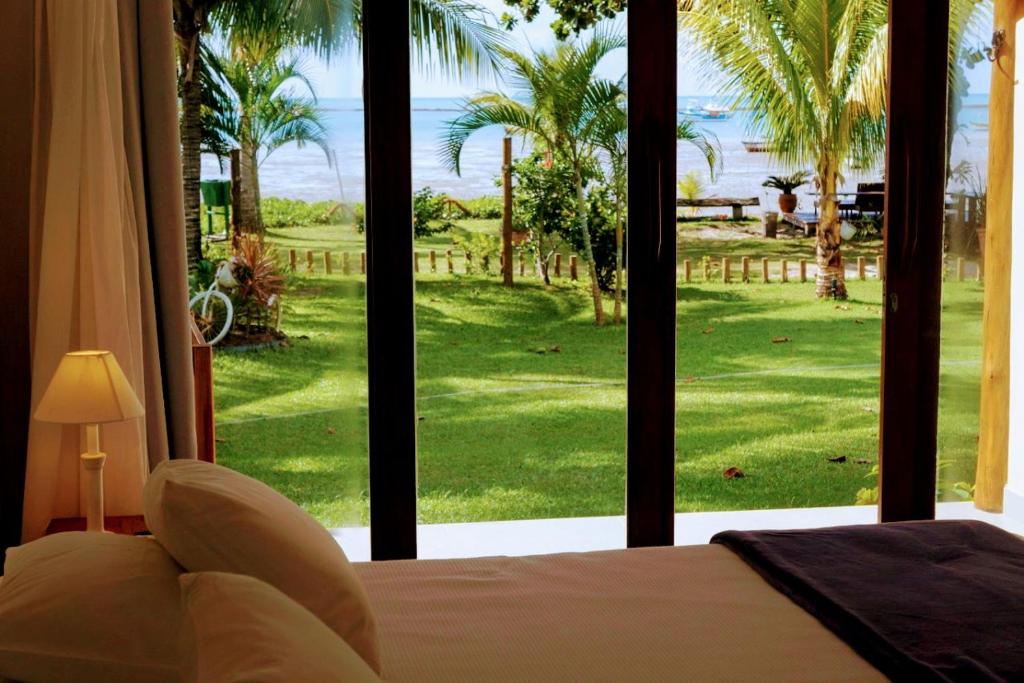 a bedroom with a large window with a view of a golf course at Pousada Areia Preta in Cumuruxatiba