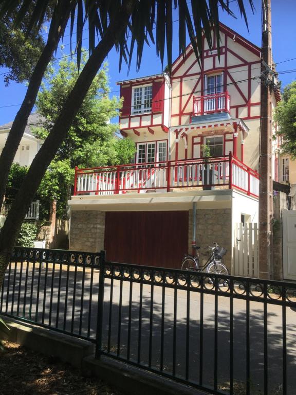 ein rotes und weißes Haus mit einem schwarzen Zaun in der Unterkunft appartement dans la Villa Colibri, in La Baule