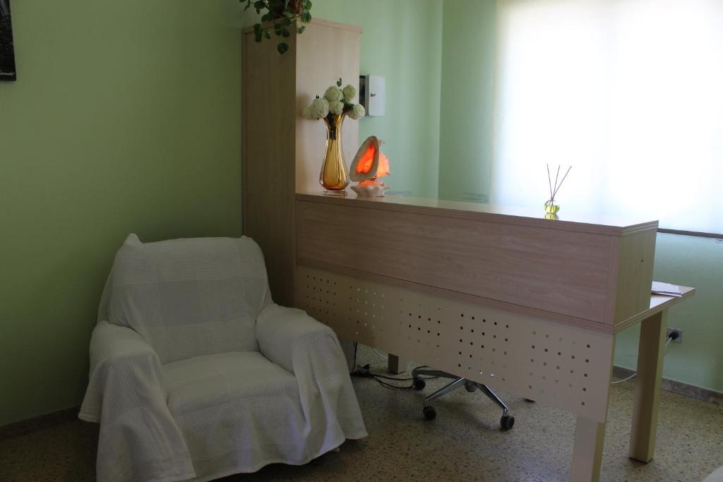 a room with a bed and a desk with a vase of flowers at Albergue Turístico Silleda in Silleda
