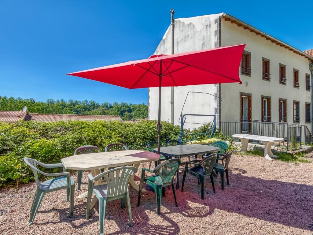 une table et des chaises avec un parapluie rouge dans l'établissement Lovely Cottage in Pontgibaud with Garden near Lake, à Pontgibaud