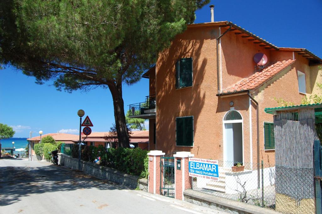 a building on the side of a street with a tree at Elbamar Procchio in Procchio