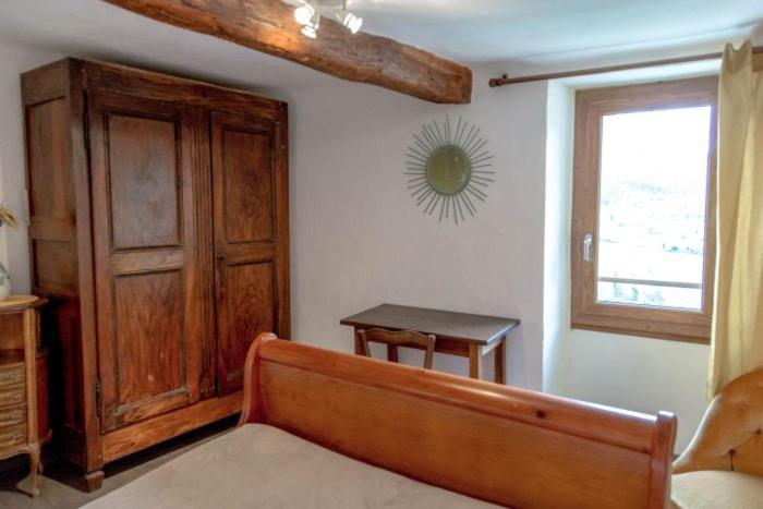 a bedroom with a bed and a wooden cabinet and a window at Gîte Chambres d&#39;hôtes Le Bellevue in Montbrun-les-Bains