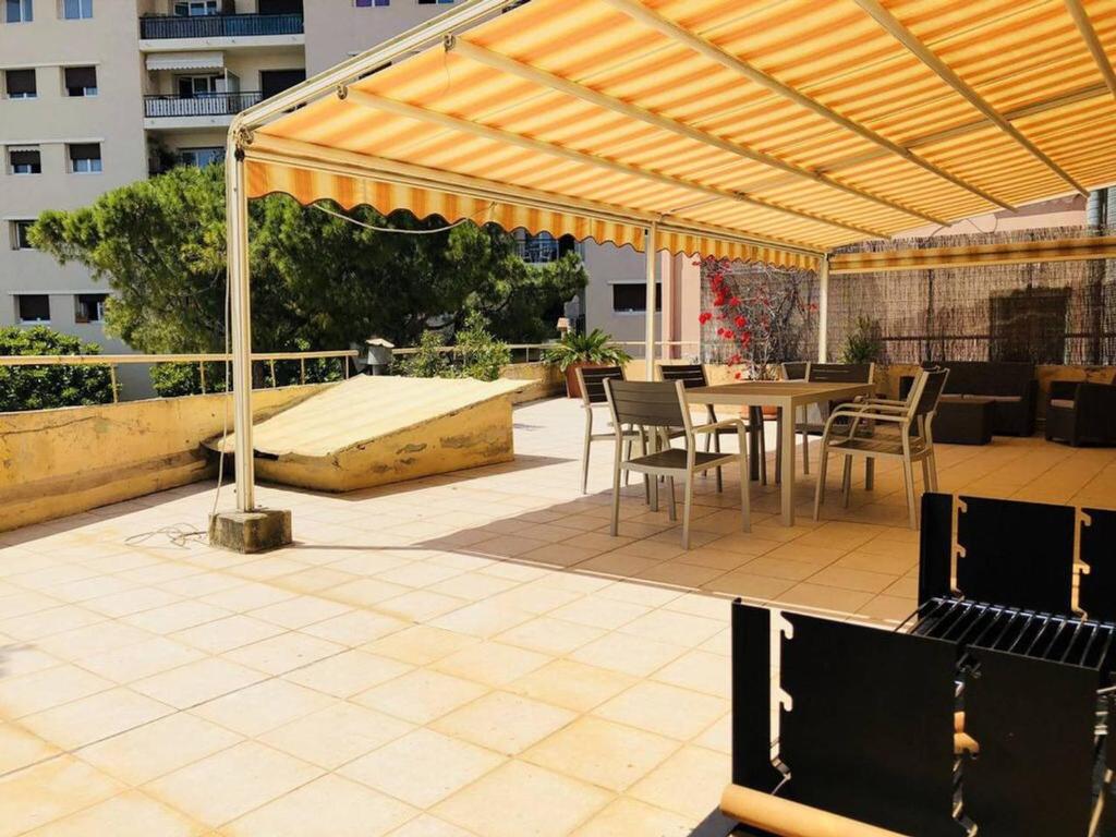 un patio avec une table et des chaises sous une pergola dans l'établissement Appartement grande terrasse à coté Monaco & plage, à Saint-Antoine
