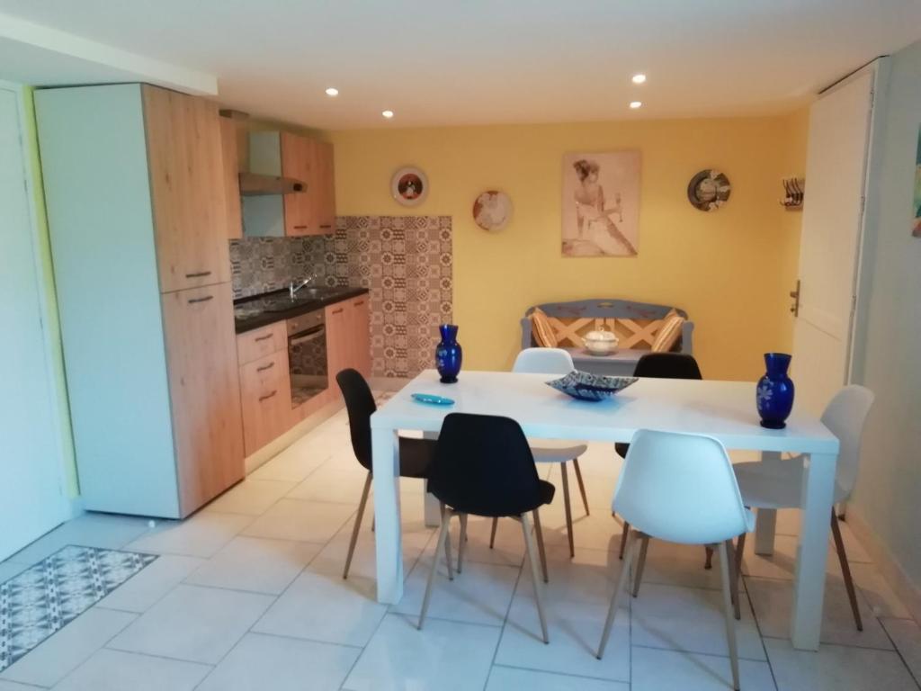 eine Küche und ein Esszimmer mit einem weißen Tisch und Stühlen in der Unterkunft Gîte le pastel in Puéchoursi