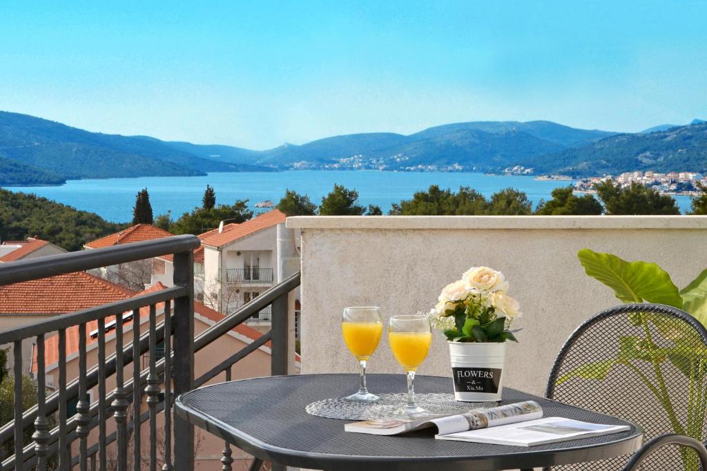 - une table avec deux verres de jus d'orange et des fleurs sur un balcon dans l'établissement Morena, à Okrug Donji