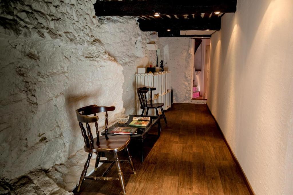 a room with chairs and a table in a stone wall at Gîte Chambres d&#39;hôtes Le Bellevue in Montbrun-les-Bains