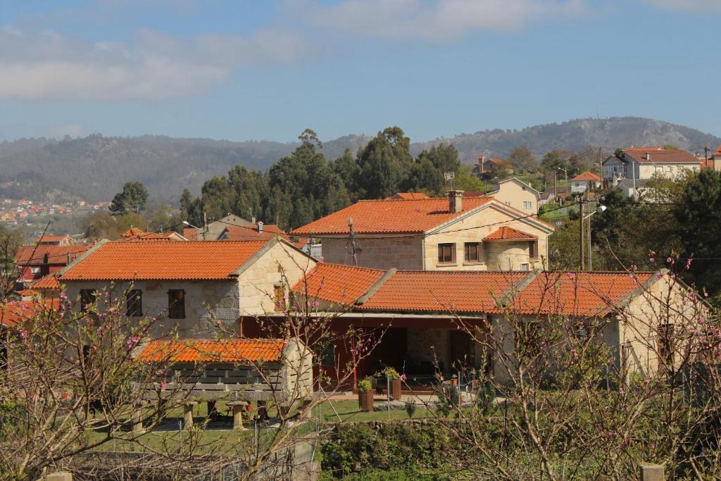 Casa Rural A Bouciña في Hio: مجموعة من المنازل بأسطح برتقالية على تلة