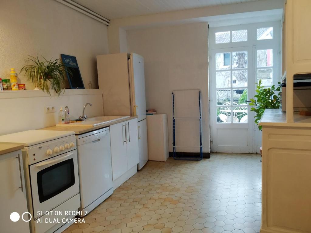 eine Küche mit weißen Geräten und einem großen Fenster in der Unterkunft Le Cerisier et Le Petit Cerisier in L'Etang des Faures 