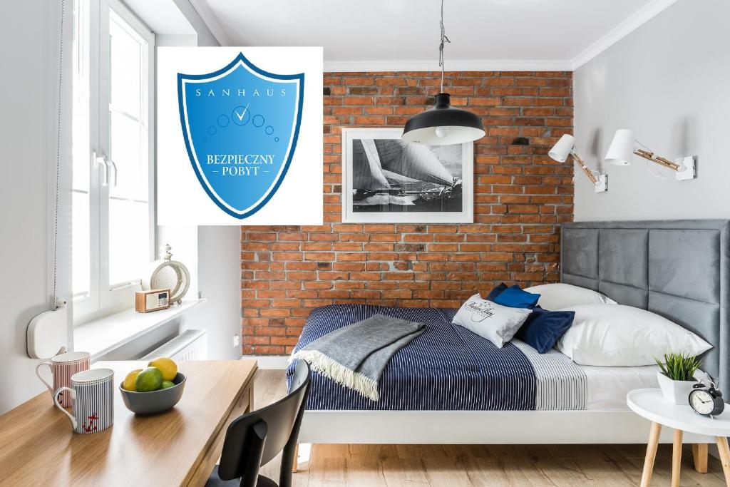 a bedroom with a bed and a brick wall at Sanhaus Apartments - Apartamenty Sailor in Sopot