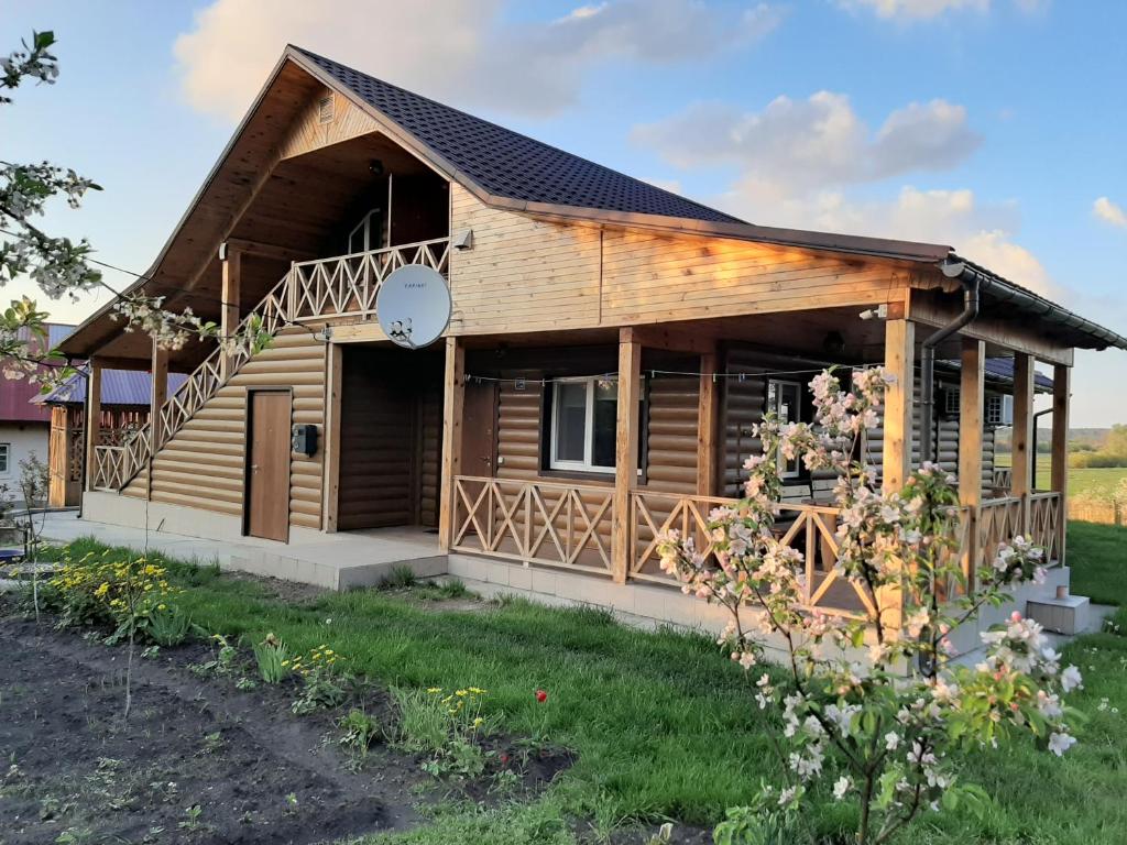 a log cabin with a porch and a clock at Гостьовий дім на Герцена Guest hous on Gertsena in Novhorod-Siversʼkyy