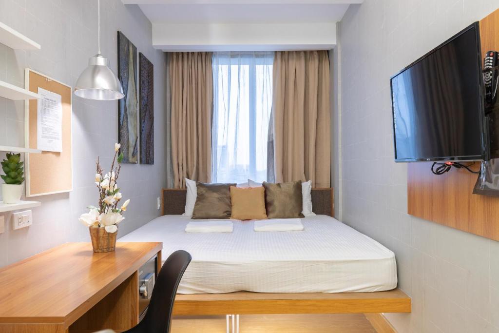 a bedroom with a bed and a desk and a television at Selah Pods Hotel Manila in Manila