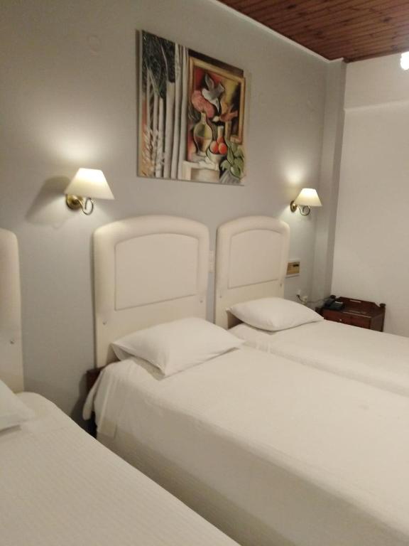 2 camas en una habitación con 2 camas blancas en Kouros Hotel, en Delfos