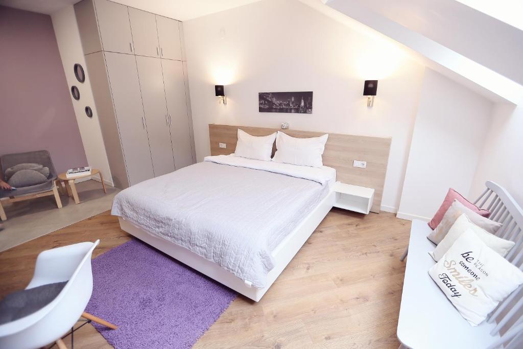 a bedroom with a white bed and a purple rug at Casa M in Oradea