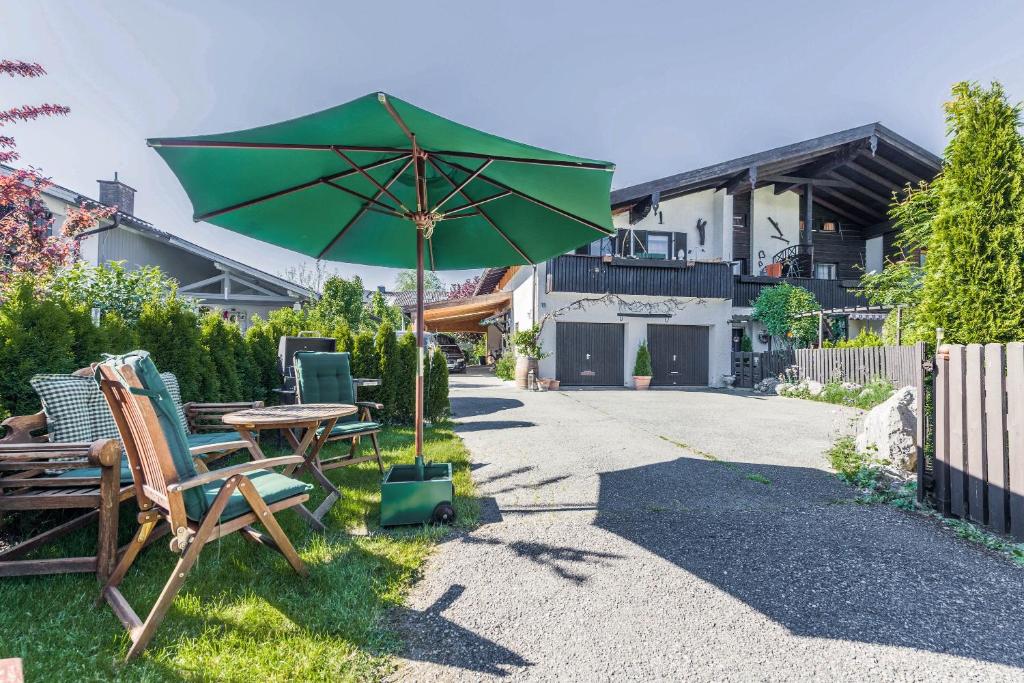 a green umbrella sitting next to a table and chairs at Zwischen Chiemsee und Bergen Ug in Bernau am Chiemsee