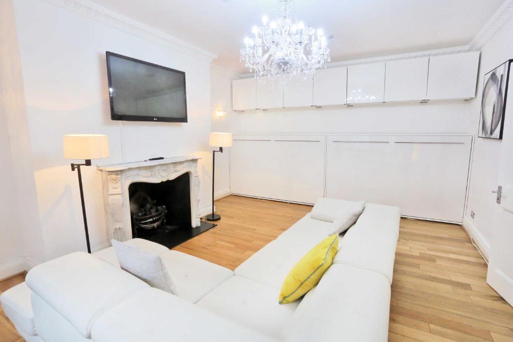 a white living room with a white couch and a fireplace at L'ambassadeur 5 room Belgravia Embassies TownHouse in London
