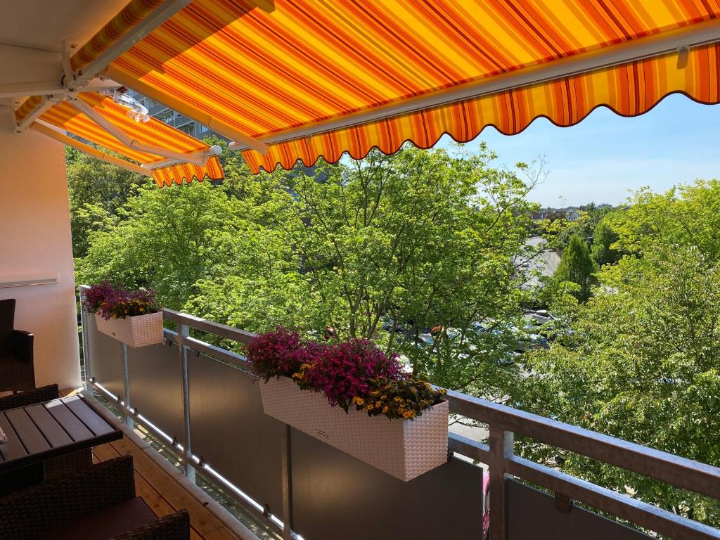 a balcony with two flower boxes and an orange umbrella at Apartment mit Sonnenbalkon und NETFLIX im Zentrum in Sankt Augustin