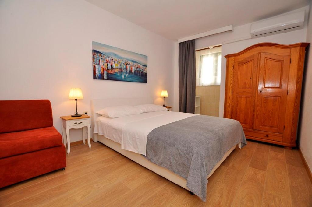 um quarto com uma cama e uma cadeira vermelha em Apartmani More em Drvenik